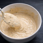 Creamy homemade smash burger sauce in a white bowl with a spoon, showing thick texture and seasoning flecks
